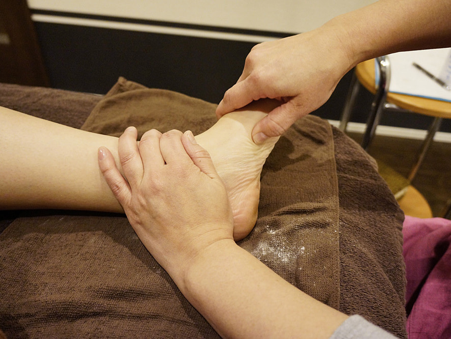 パウダーで足の踵を施術している